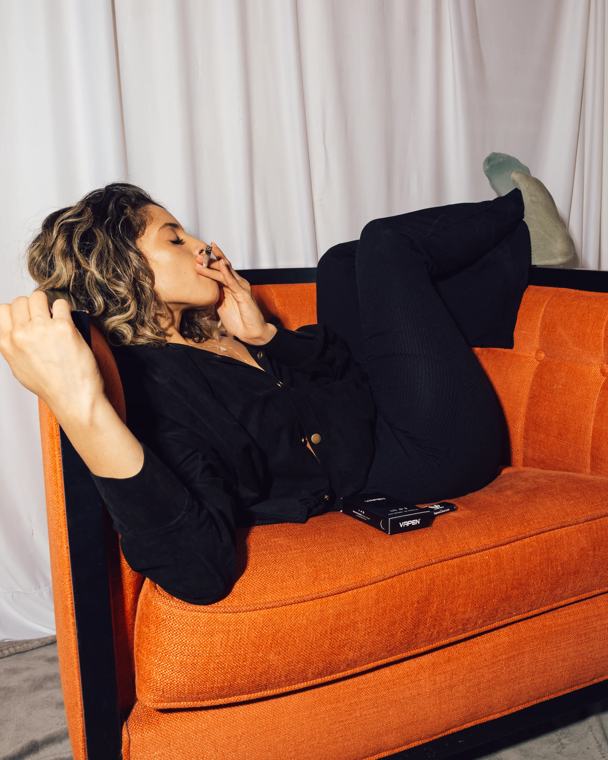 Lifestyle photo of a woman with a pre-roll on an orange chair