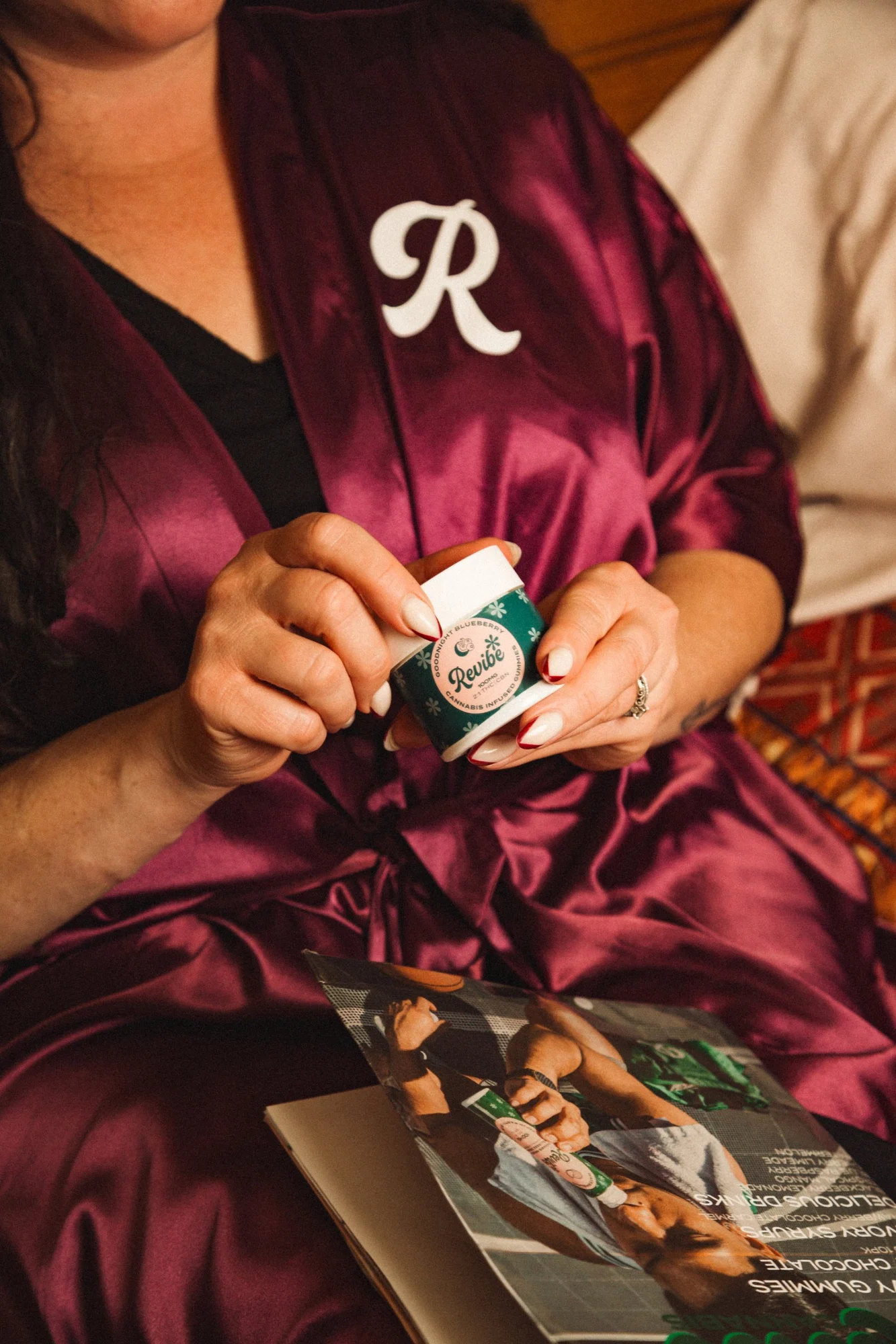 Woman in a plum Revibe robe holding a Goodnight Blueberry gummy jar