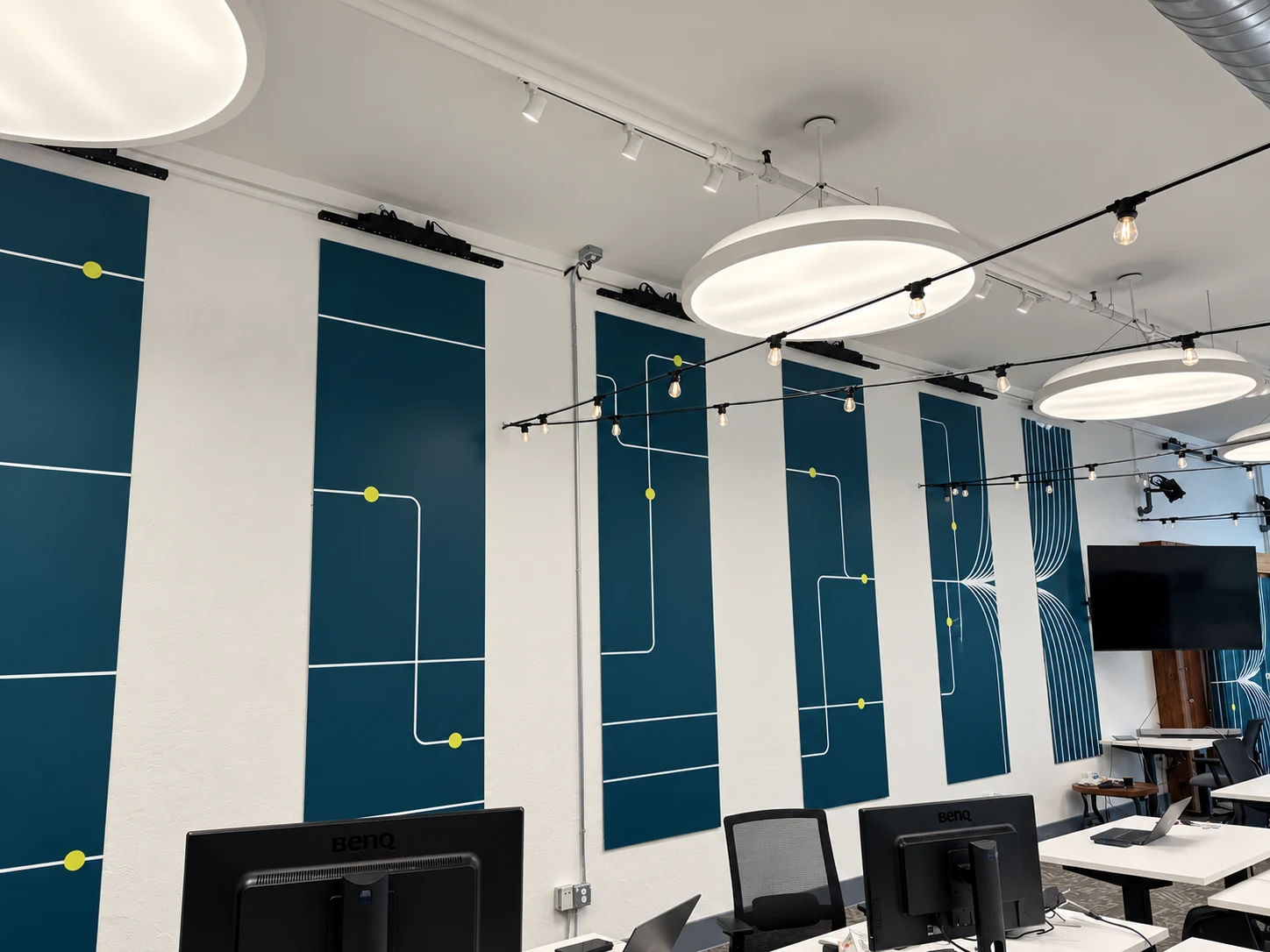 Revive Innovation Hub workspace with tall teal wall panels of white path lines and lime dots