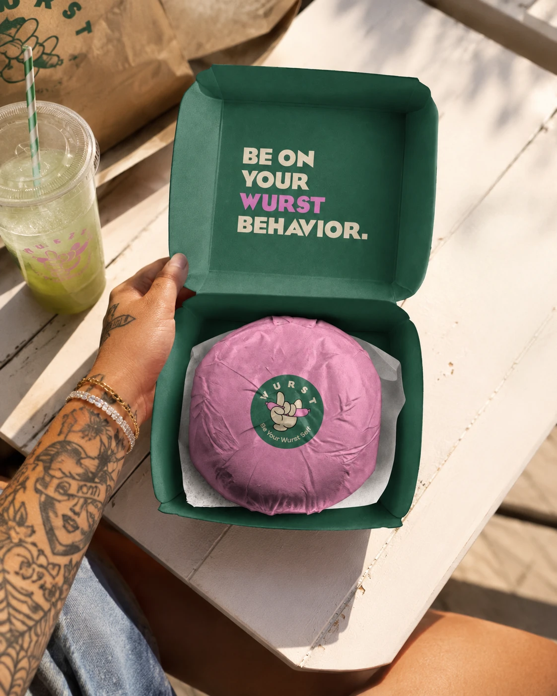 Open Wurst burger box reading Be on your Wurst behavior, with a pink-wrapped burger inside