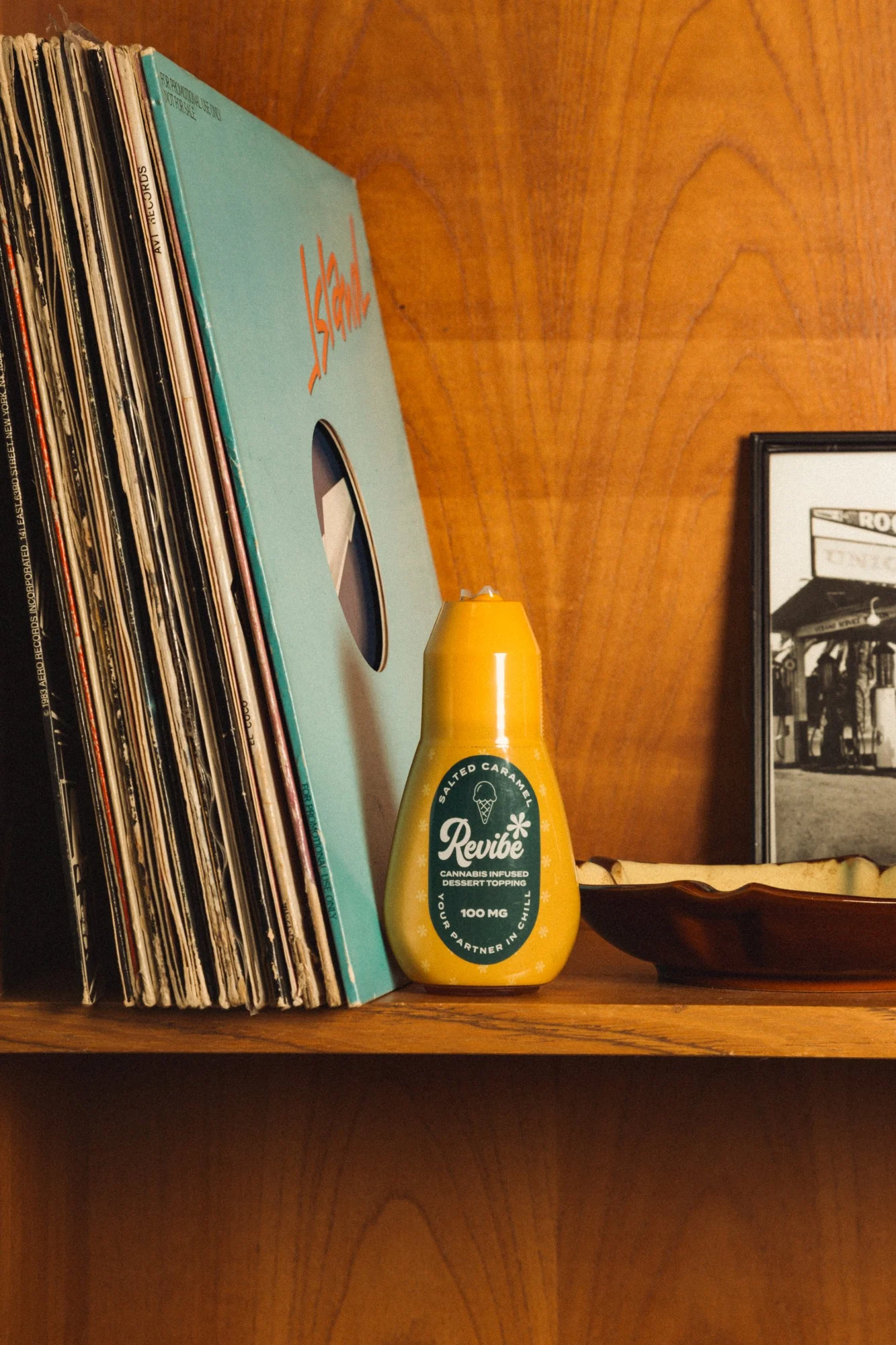 Revibe salted caramel dessert topping on a wood shelf next to records