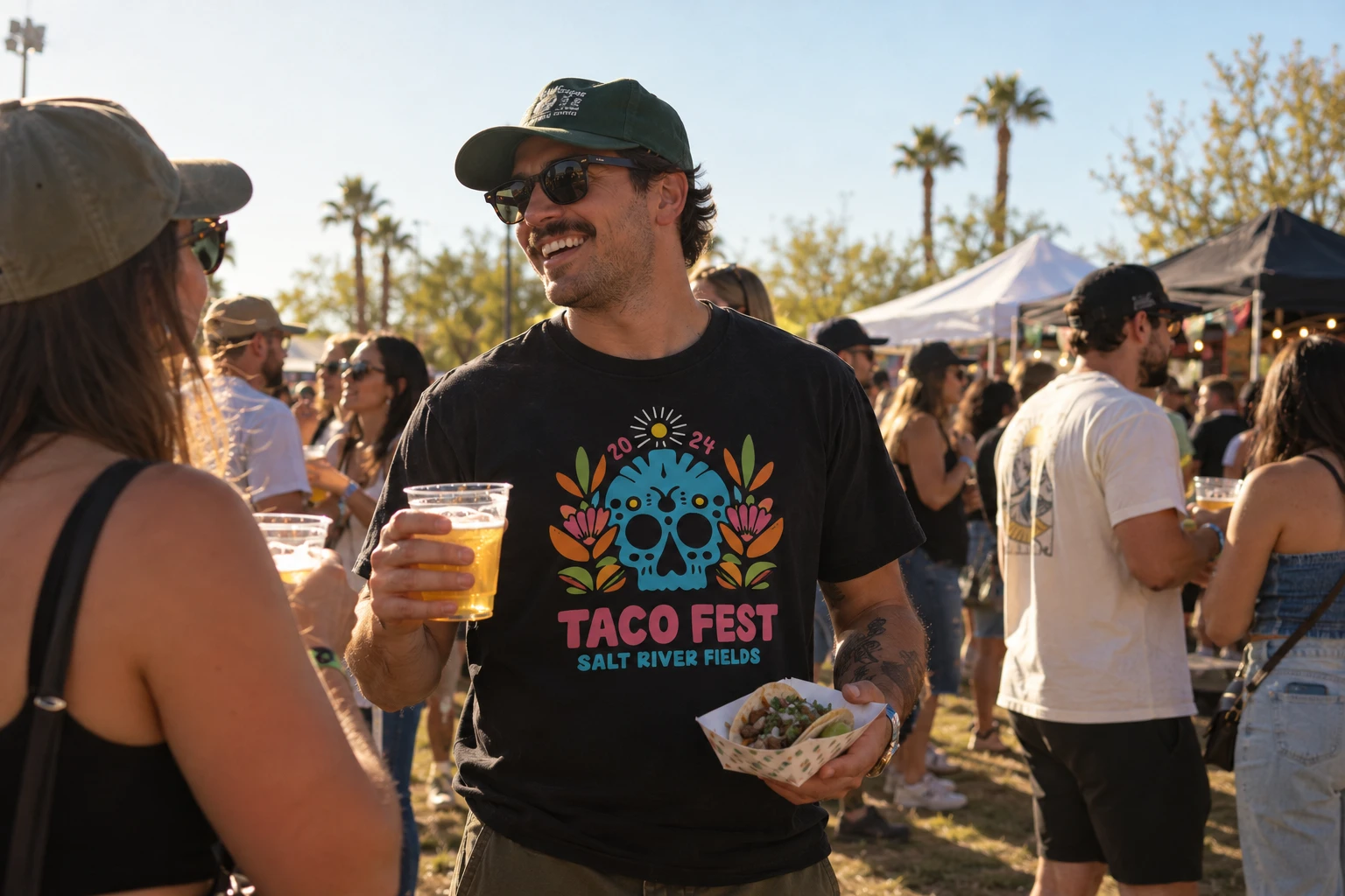 Festival-goer in a black Taco Fest 2024 tee holding a beer and a taco