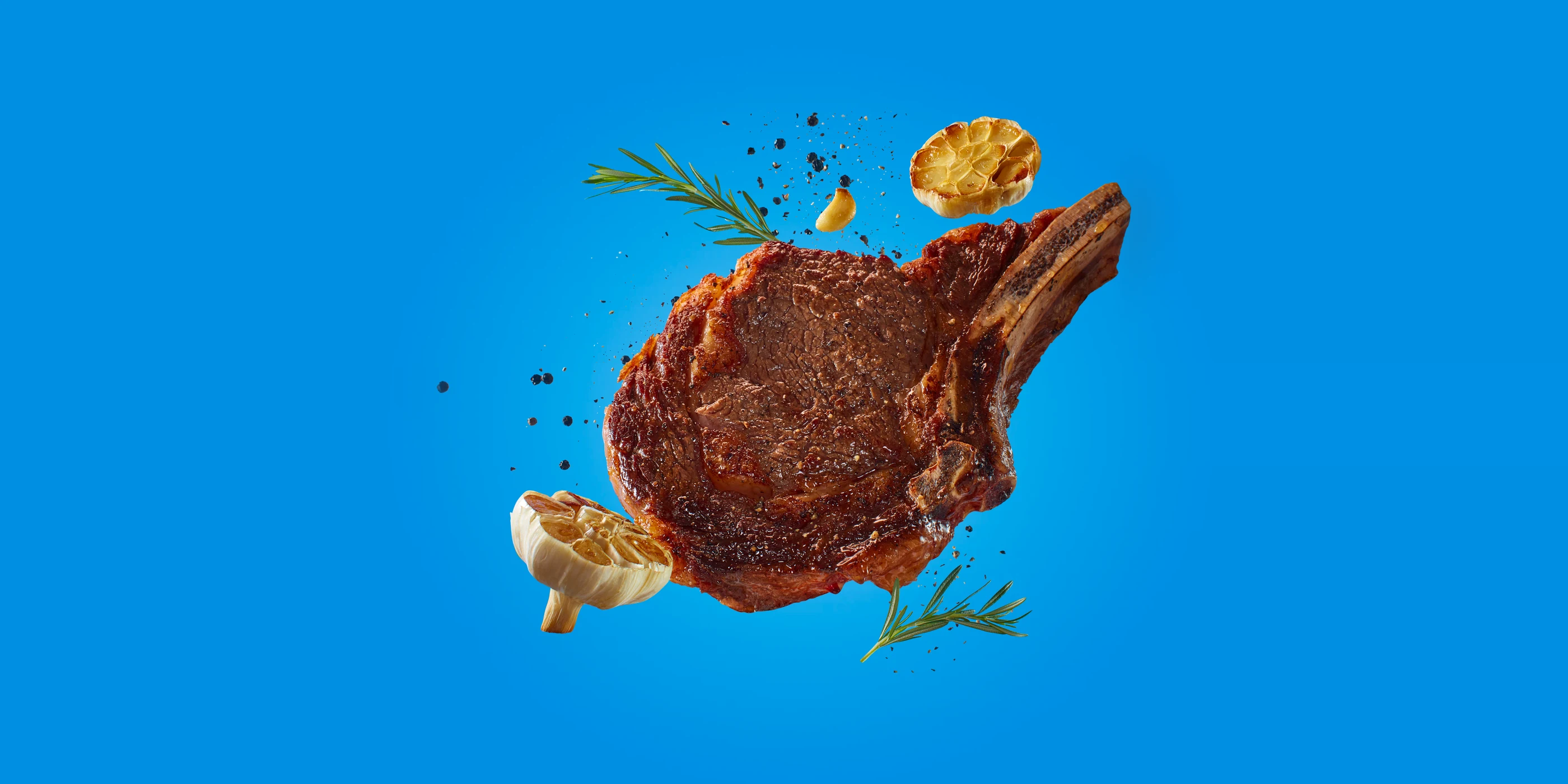 Kroger campaign: a bone-in ribeye floating with garlic and rosemary on blue