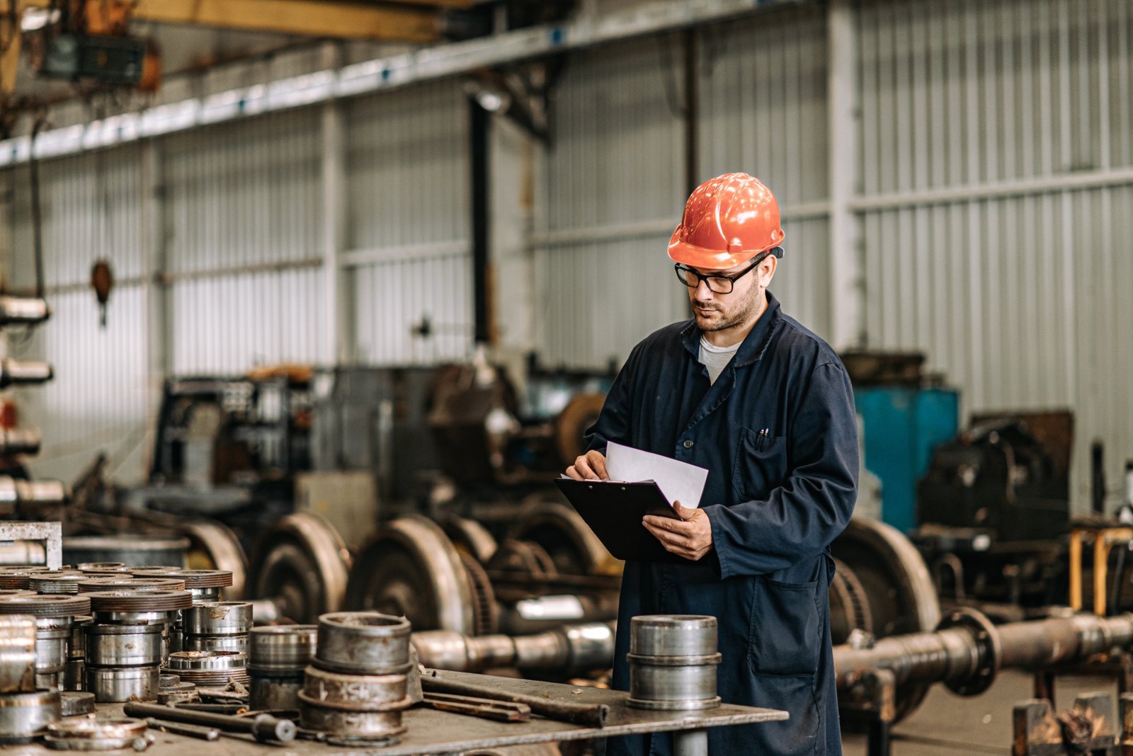 Factory worker in a hard hat reviewing a clipboard